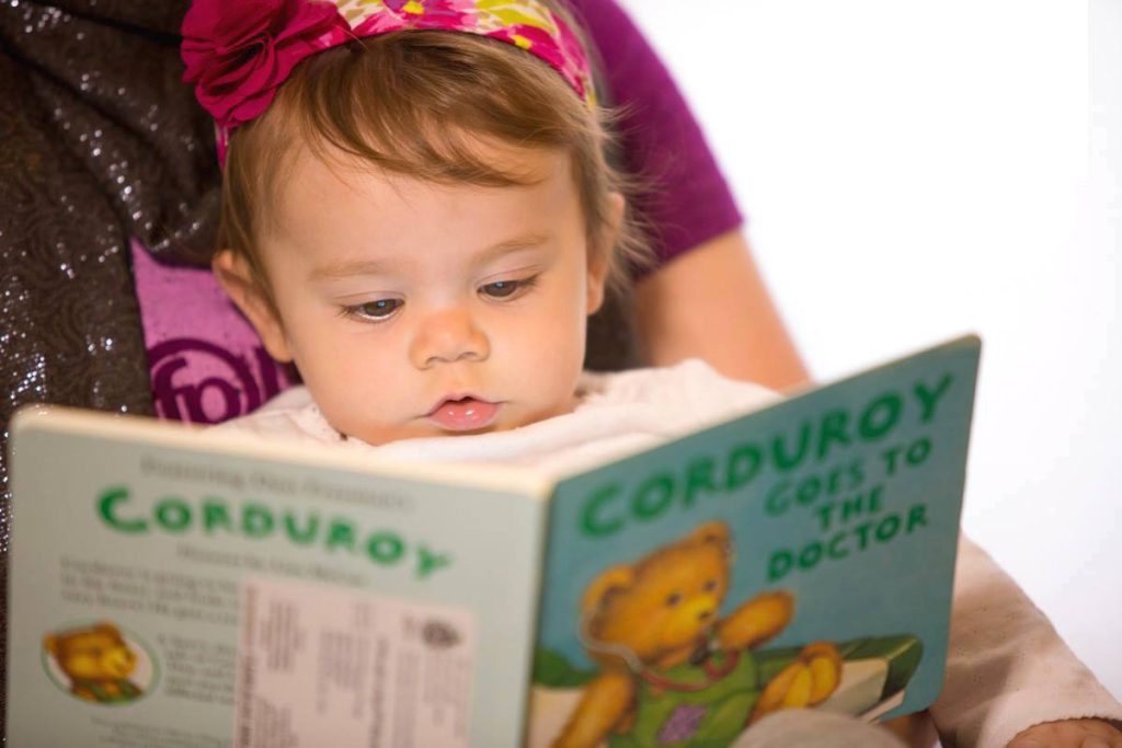 Baby reading a book with an adult